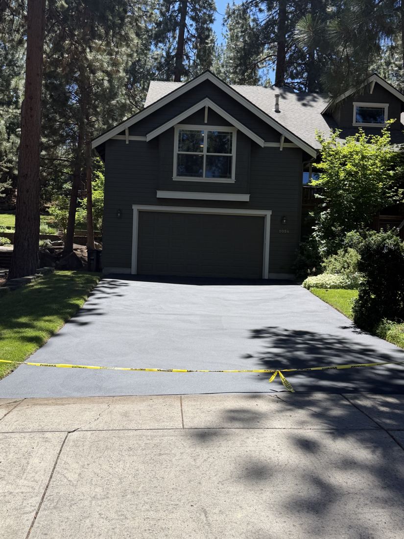 After: the same driveway freshly sealed, taped off at the sidewalk